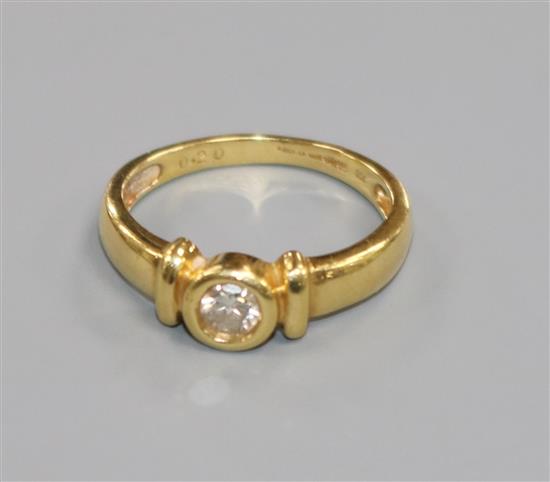 A modern 18ct gold and collet set solitaire diamond ring, size M.